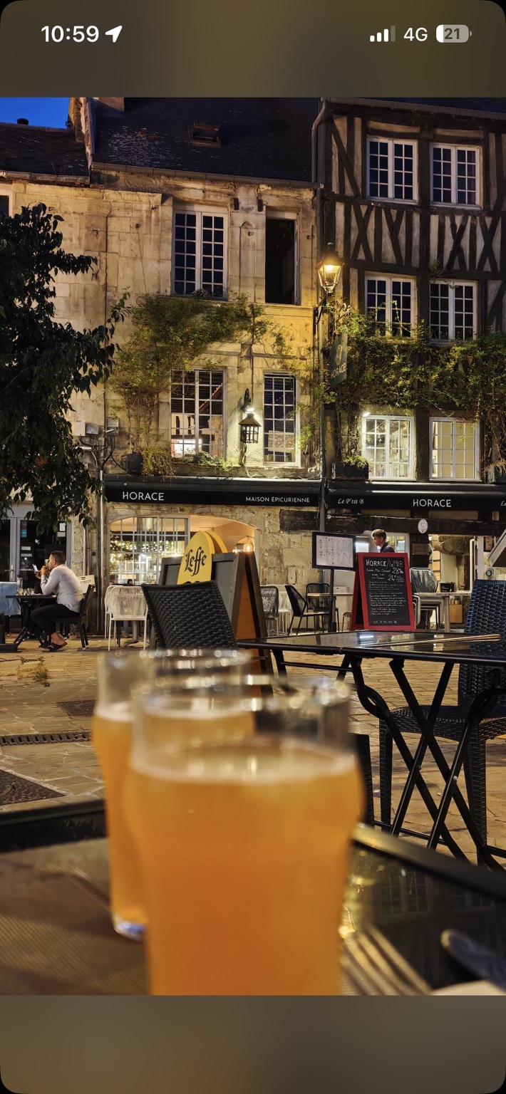 Vue sur les façades du Vaugueux illuminées le soir, avec deux verres au premier plan